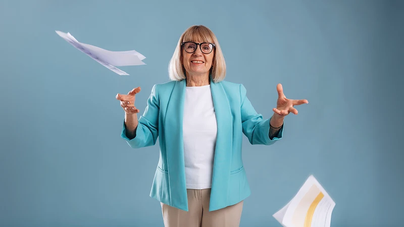 Senior woman happily throwing financial paperwork in the air, illustrating the ease of low-doc and no-income-verification home equity options.